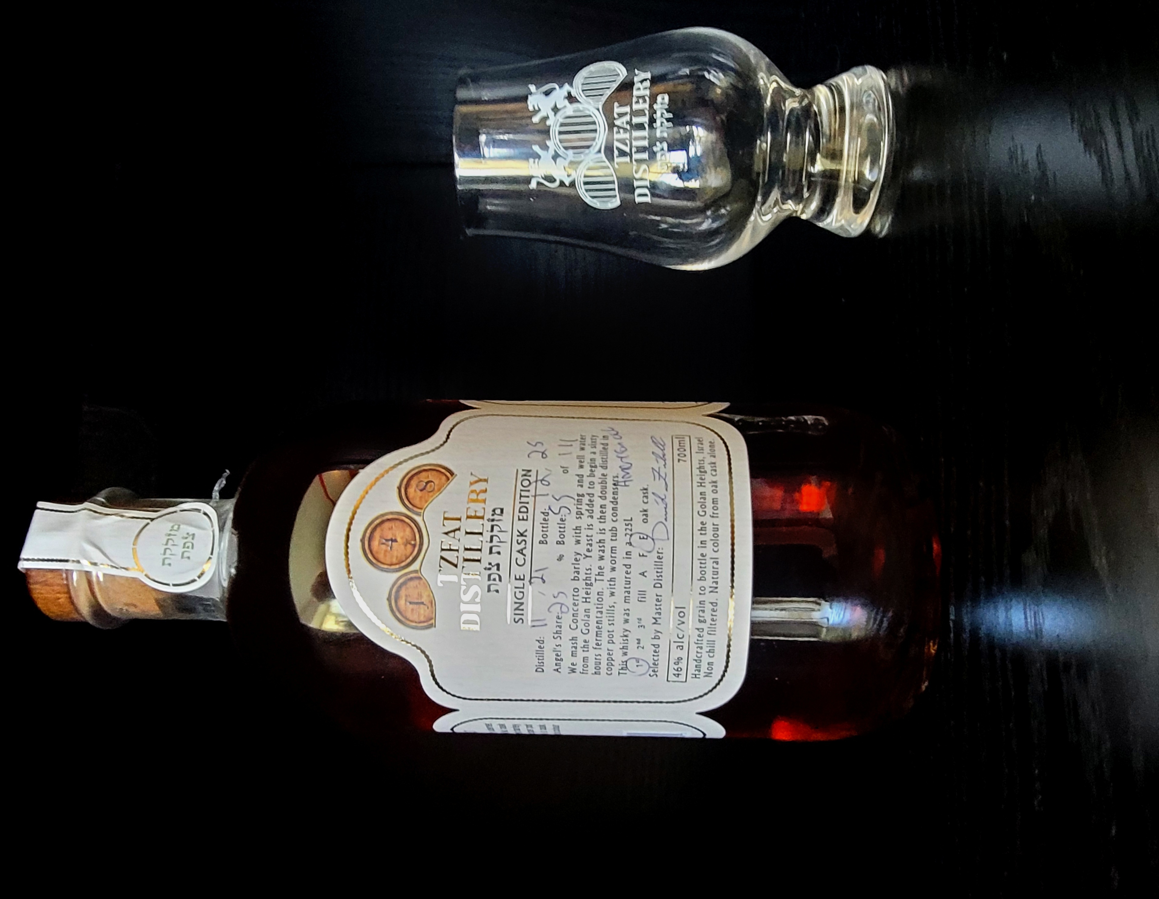 Tzfat Distillery single cask bottle, no. 55 of 111, beside its etched tasting glass